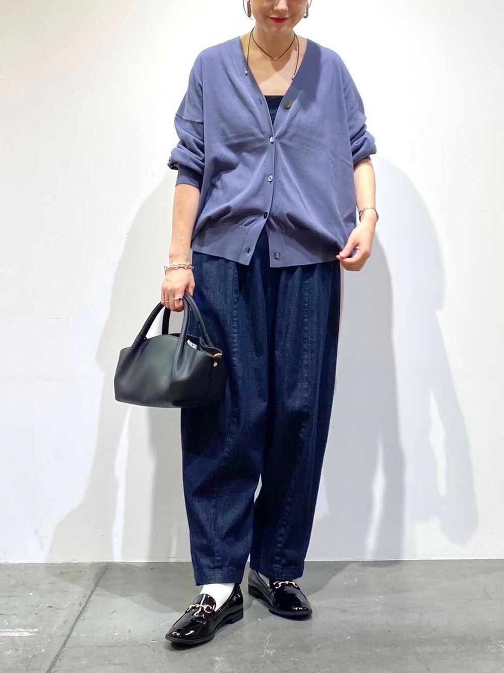 ブラック系のローファー、ブルー系のデニムパンツ、ブルー系のカーディガン/ボレロを着用したレディースの秋コーディネートの5枚目の写真