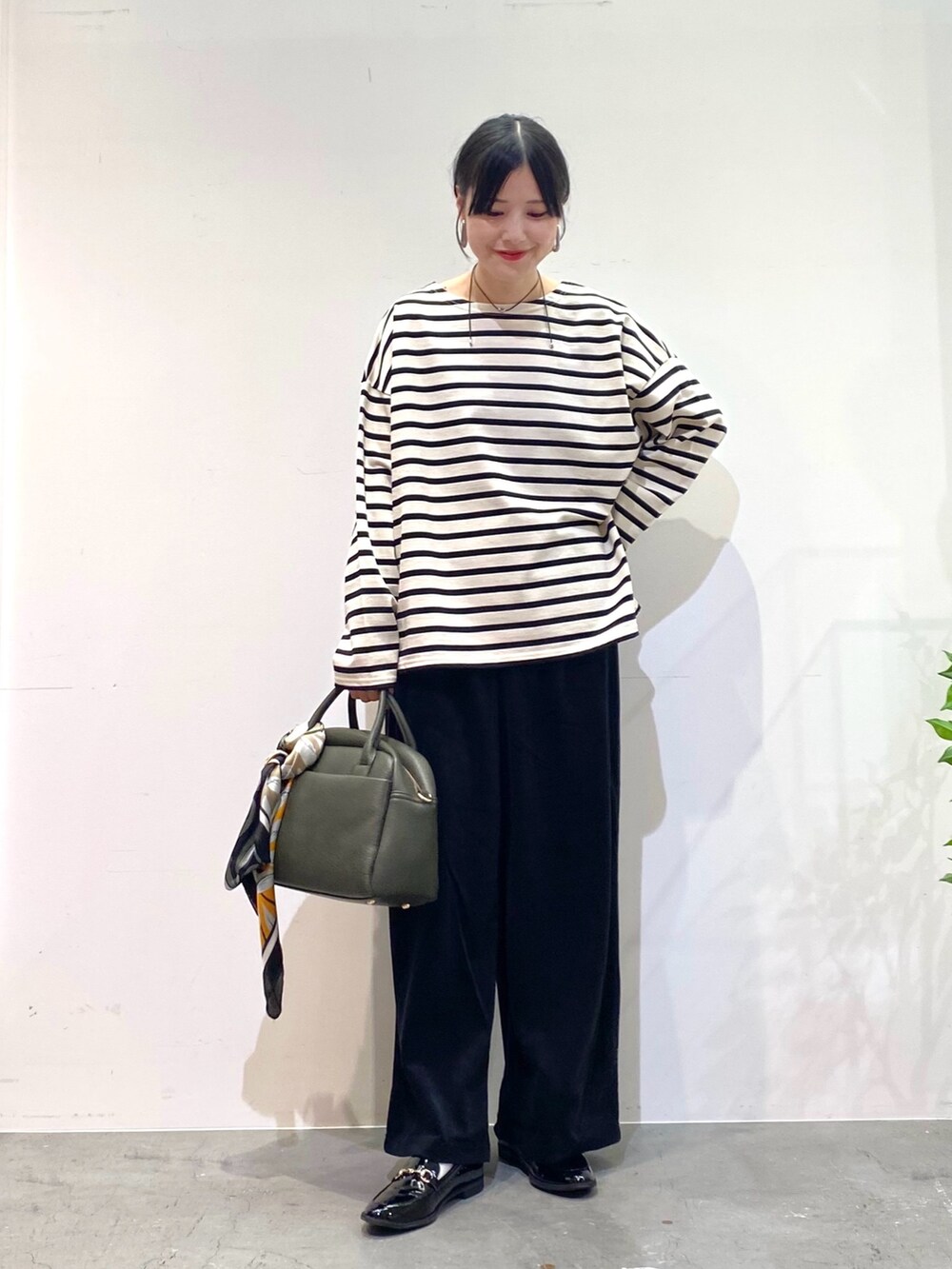 ホワイト系のTシャツ/カットソー、ブラック系のその他パンツ、グリーン系のボストンバッグを着用したレディースの秋コーディネートの3枚目の写真