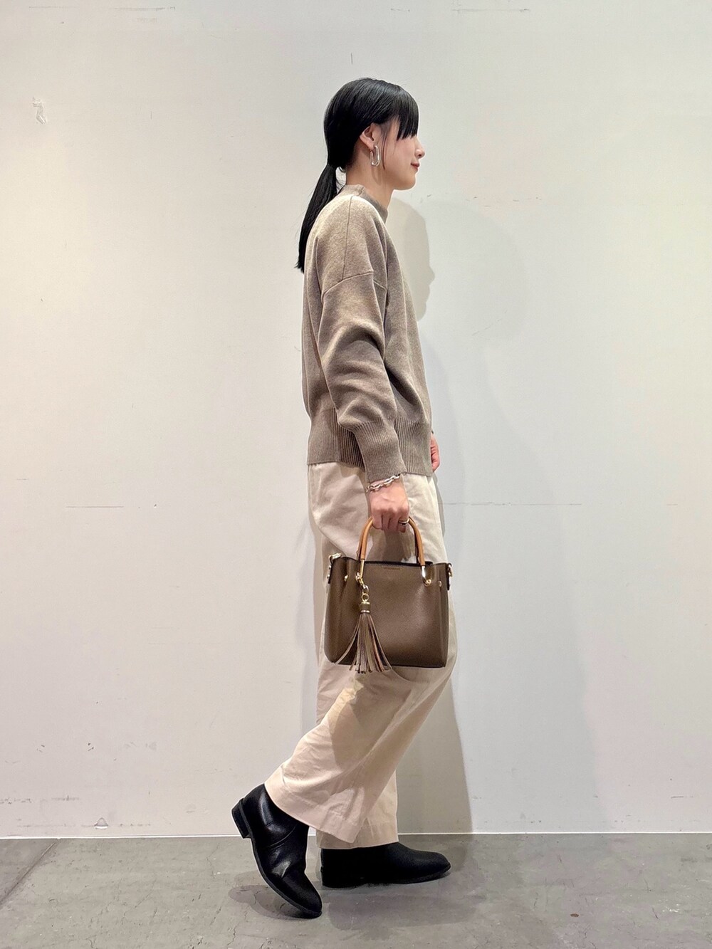 ブラック系のその他アウター、ベージュ系のニット/セーター、ホワイト系のその他パンツを着用したレディースの冬コーディネートの5枚目の写真