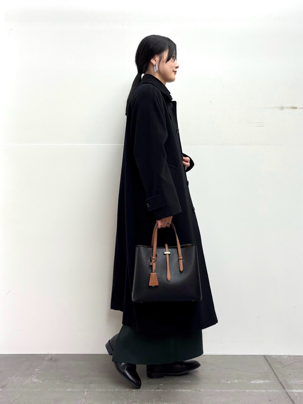 ブラック系のその他アウター、ブラック系のニット/セーター、グリーン系のスカートを着用したレディースの冬コーディネートの2枚目の写真