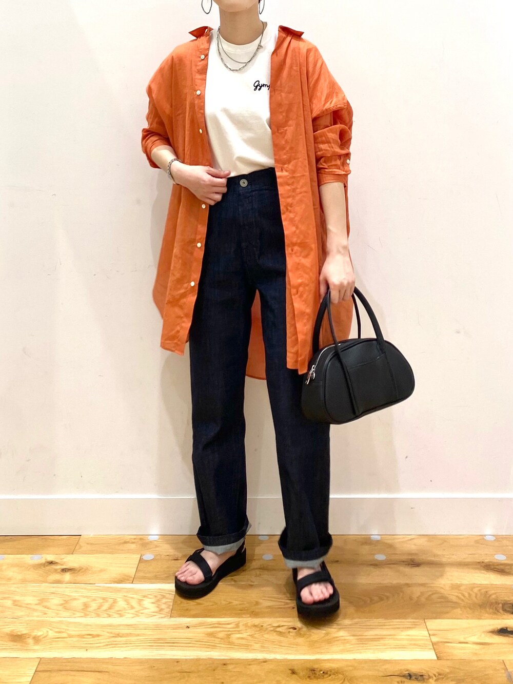 オレンジ系のシャツ/ブラウス、ホワイト系のTシャツ/カットソー、ブルー系のデニムパンツを着用したレディースの春コーディネートの4枚目の写真