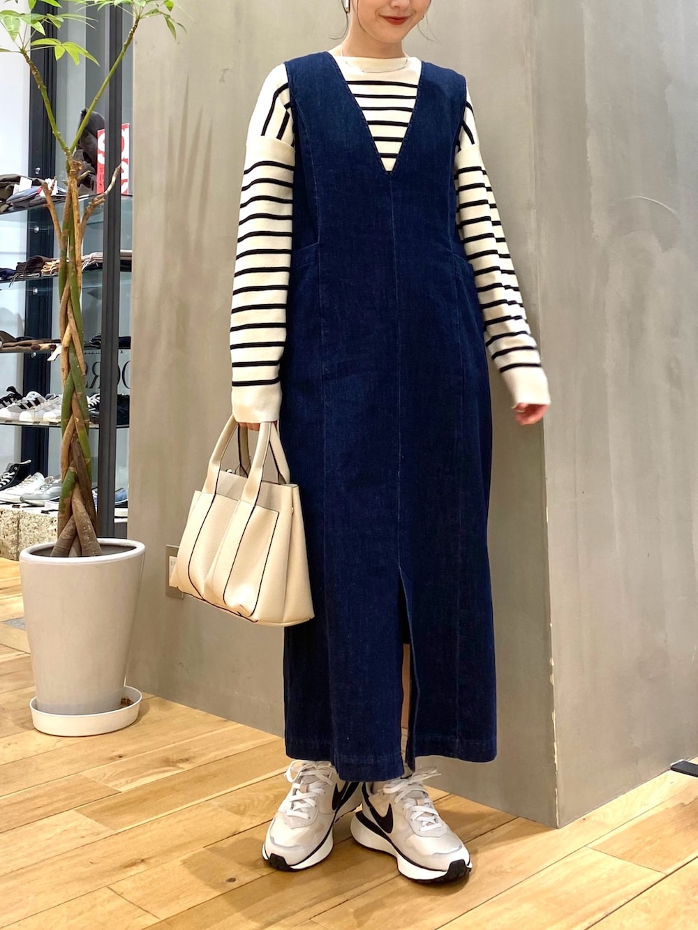 ホワイト系のニット/セーター、ブルー系のジャンパースカート、ホワイト系のトートバッグを着用したレディースの冬コーディネートの3枚目の写真