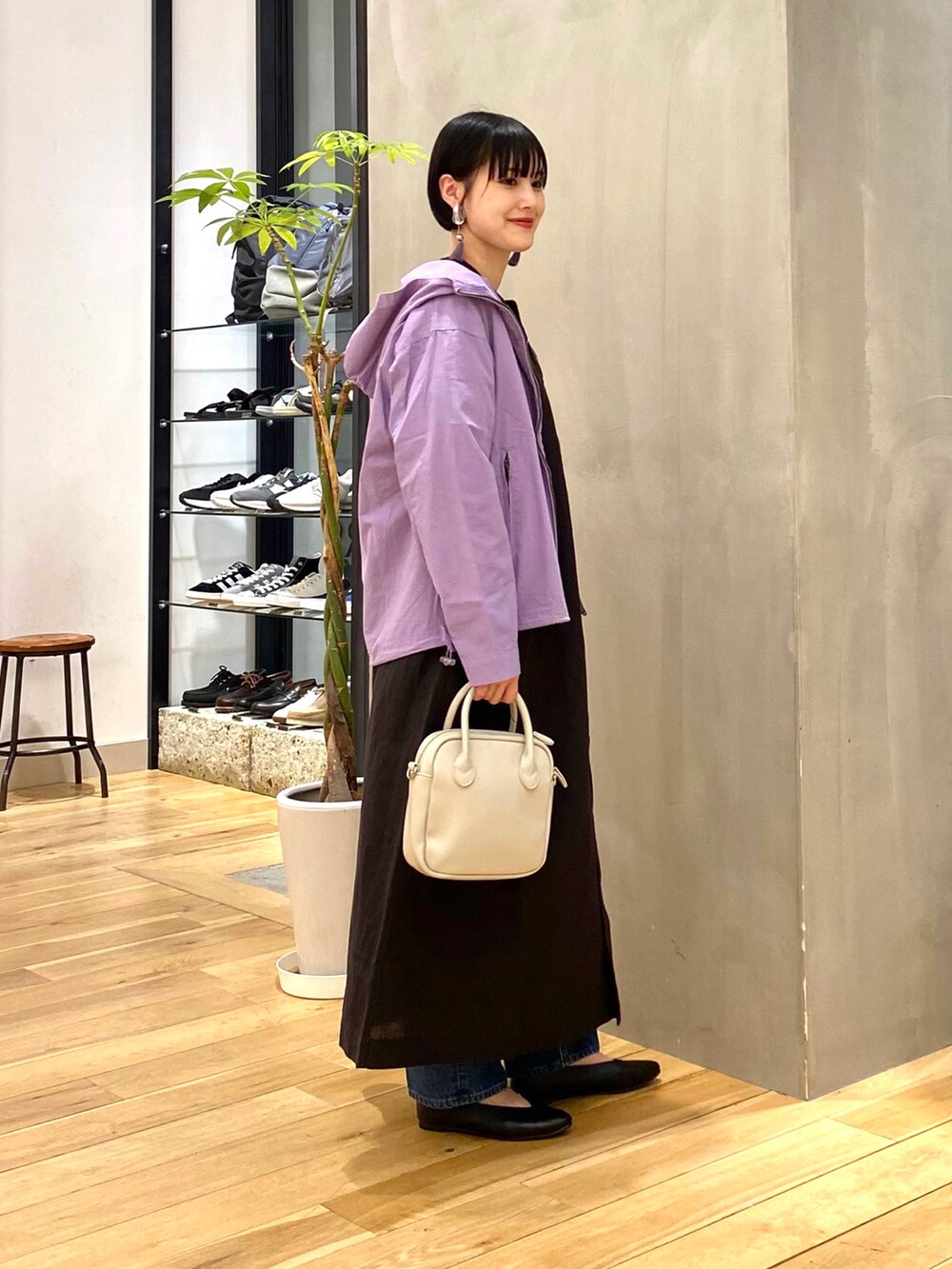 パープル系のブルゾン、ブルー系のデニムパンツ、ベージュ系のショルダーバッグを着用したレディースの春コーディネートの4枚目の写真