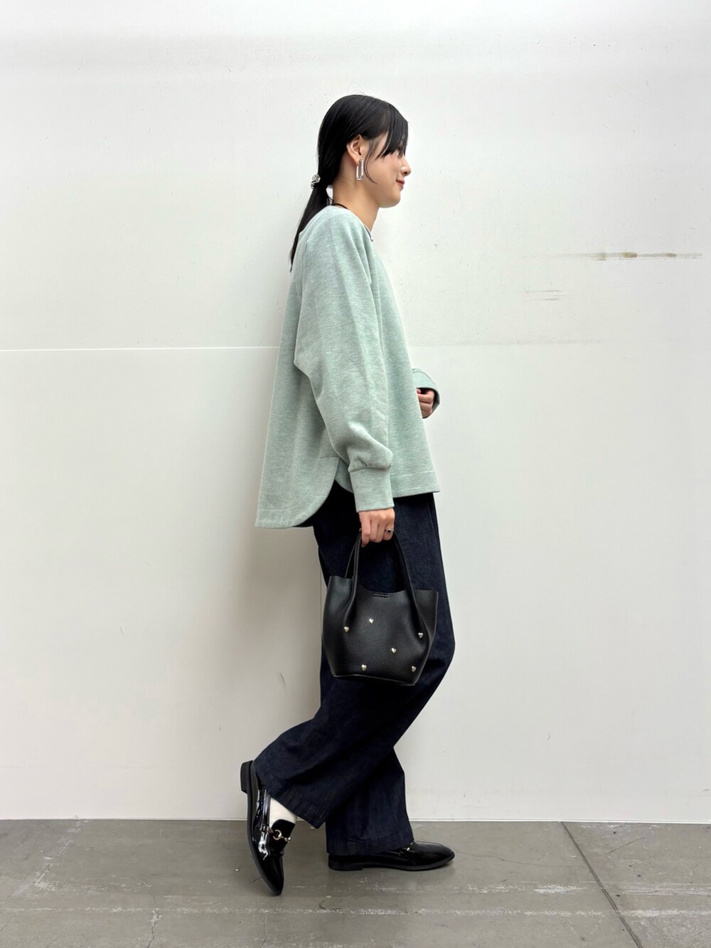 グリーン系のTシャツ/カットソー、ブルー系のデニムパンツ、ブラック系のショルダーバッグを着用したレディースの冬コーディネートの3枚目の写真