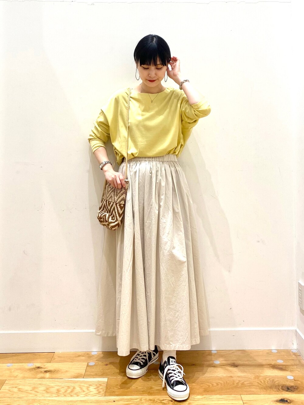 イエロー系のTシャツ/カットソー、ホワイト系のスカート、ブラウン系のショルダーバッグを着用したレディースの春コーディネートの2枚目の写真