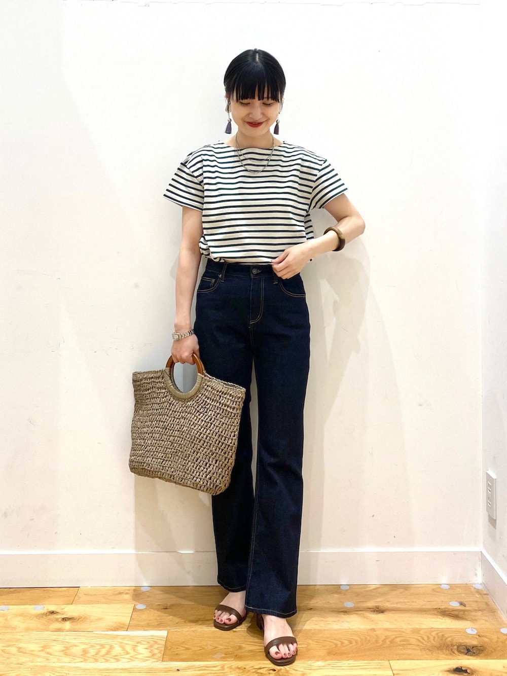 グリーン系のTシャツ/カットソー、ブルー系のデニムパンツ、グレー系のトートバッグを着用したレディースの春コーディネートの2枚目の写真