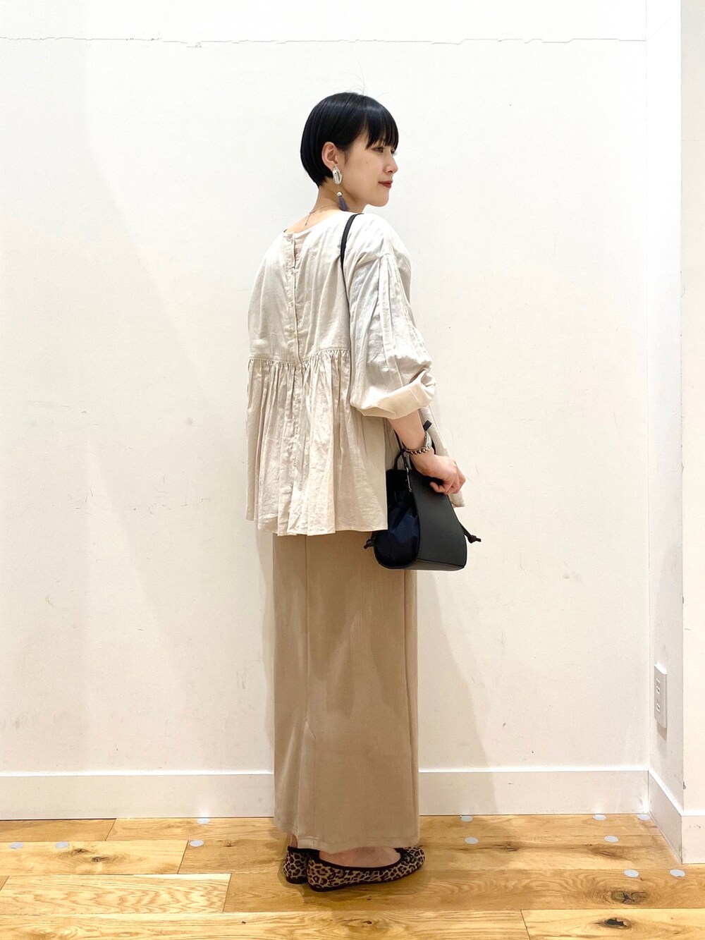 グレー系のシャツ/ブラウス、ベージュ系のスカート、ブラック系のショルダーバッグを着用したレディースの春コーディネートの4枚目の写真