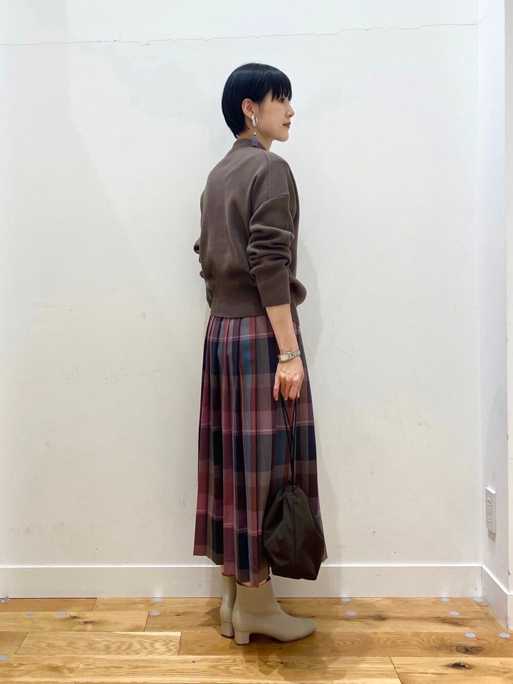 ブルー系のチェスターコート、ブラウン系のニット/セーター、パープル系のスカートを着用したレディースの秋コーディネートの5枚目の写真