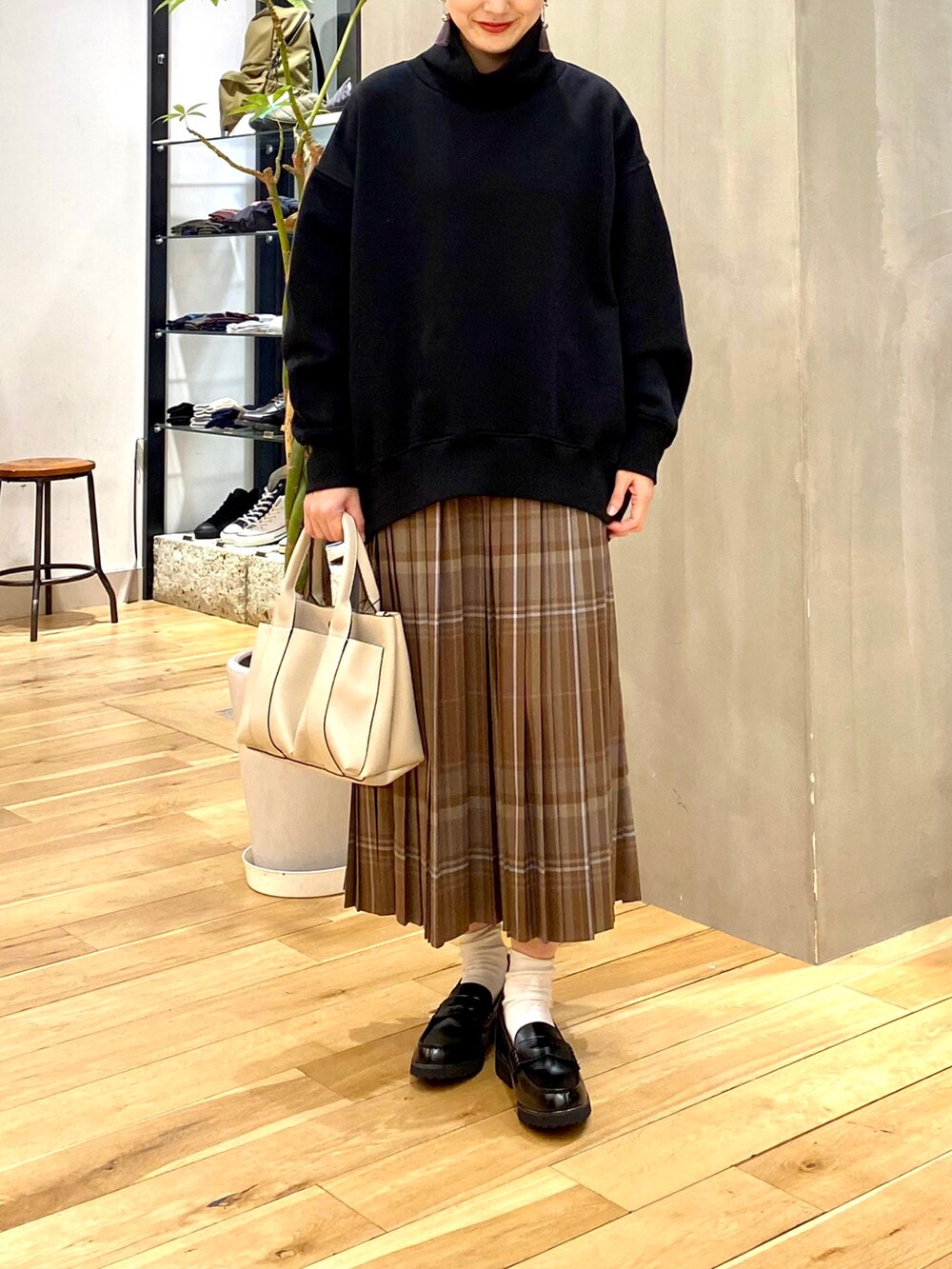ブラック系のスウェット、ブラウン系のスカート、ホワイト系のトートバッグを着用したレディースの冬コーディネートの4枚目の写真