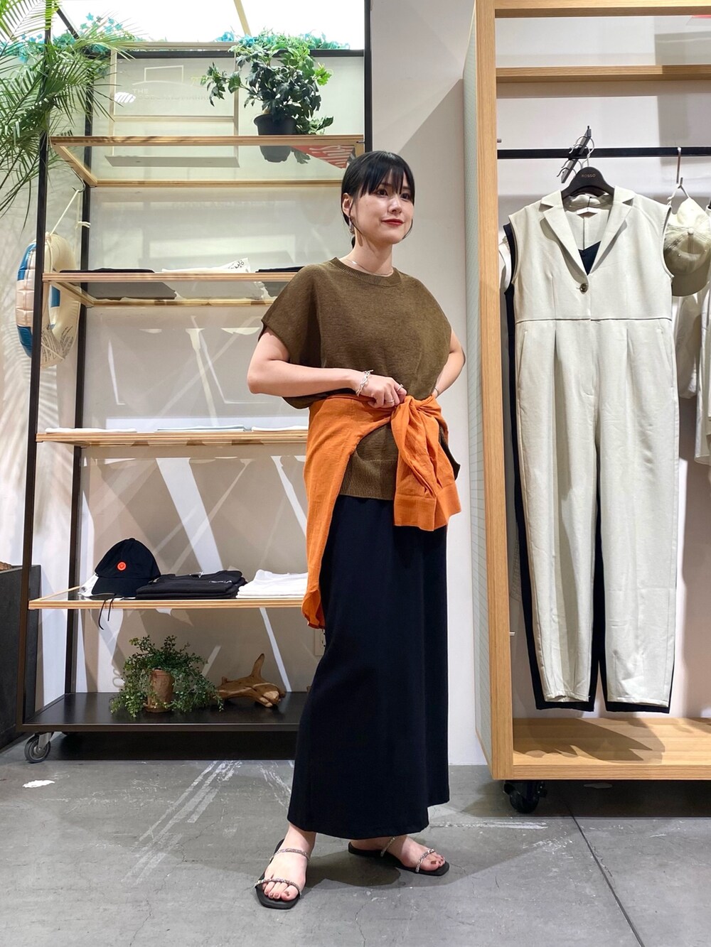ブラウン系のニット/セーター、オレンジ系のシャツ/ブラウス、ブラック系のスカートを着用したレディースの夏コーディネートの4枚目の写真