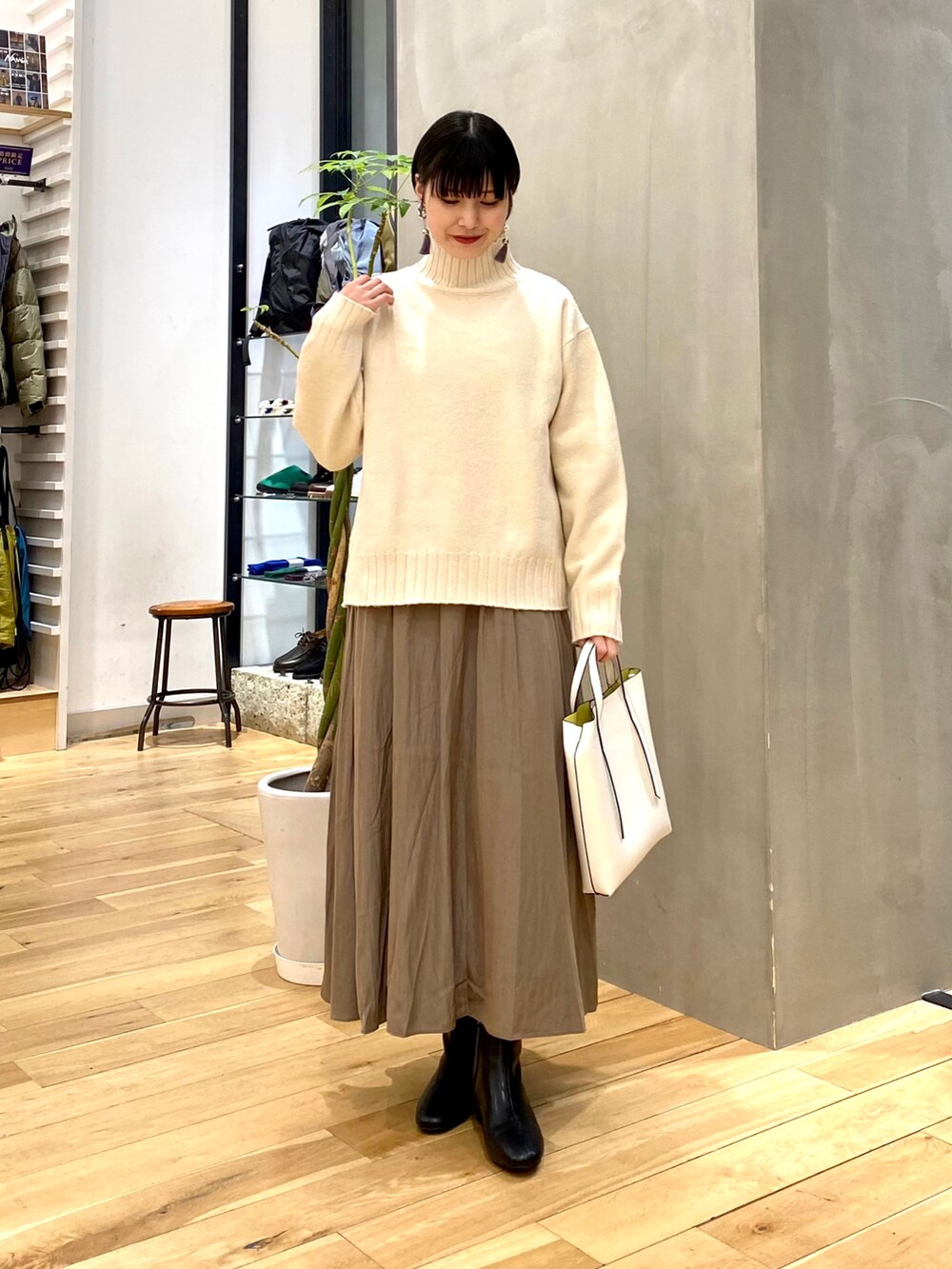 ベージュ系のダウンジャケット/コート、ホワイト系のニット/セーター、ブラウン系のスカートを着用したレディースの冬コーディネートの3枚目の写真