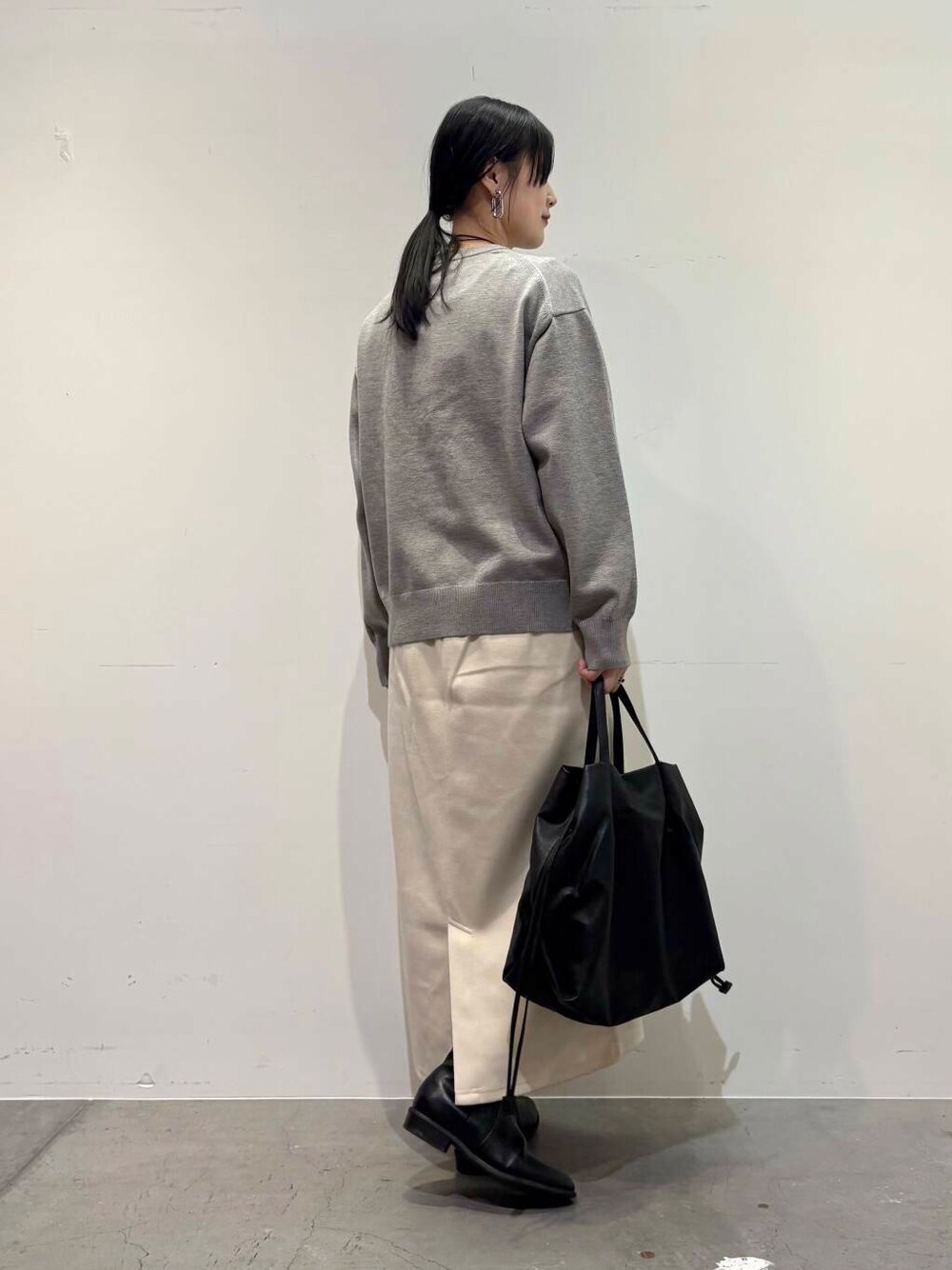 ブラック系のトートバッグ、ブラック系のブーツ、ホワイト系のスカートを着用したレディースの冬コーディネートの3枚目の写真