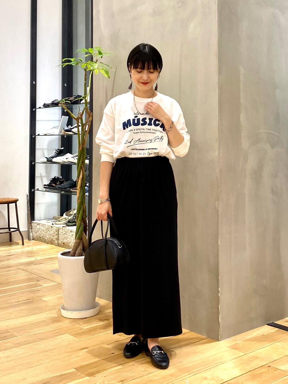 ホワイト系のTシャツ/カットソー、ブラック系のスカート、ブラック系のショルダーバッグを着用したレディースの秋コーディネートの3枚目の写真