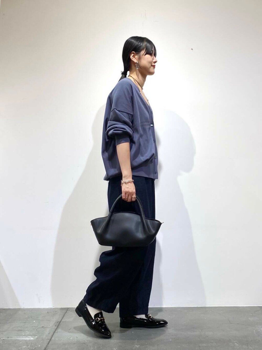 ブラック系のローファー、ブルー系のデニムパンツ、ブルー系のカーディガン/ボレロを着用したレディースの秋コーディネートの2枚目の写真