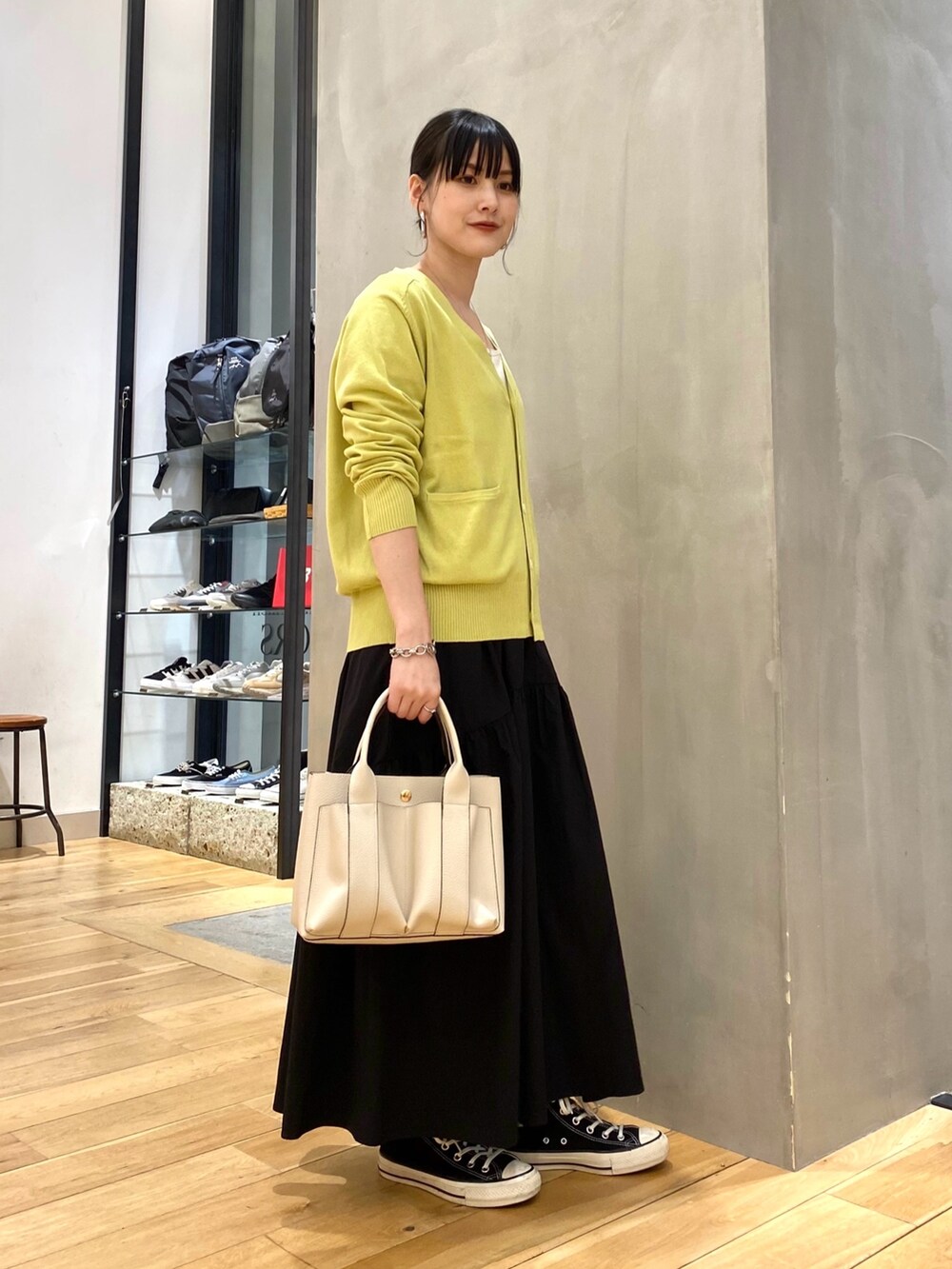グリーン系のカーディガン/ボレロ、ブラック系のスカート、ホワイト系のトートバッグを着用したレディースの春コーディネートの2枚目の写真