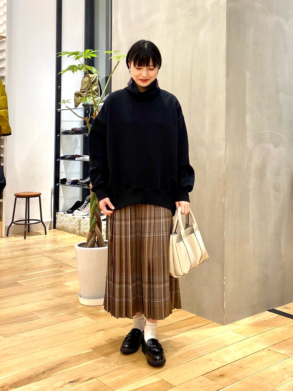 ブラック系のスウェット、ブラウン系のスカート、ホワイト系のトートバッグを着用したレディースの冬コーディネートの2枚目の写真