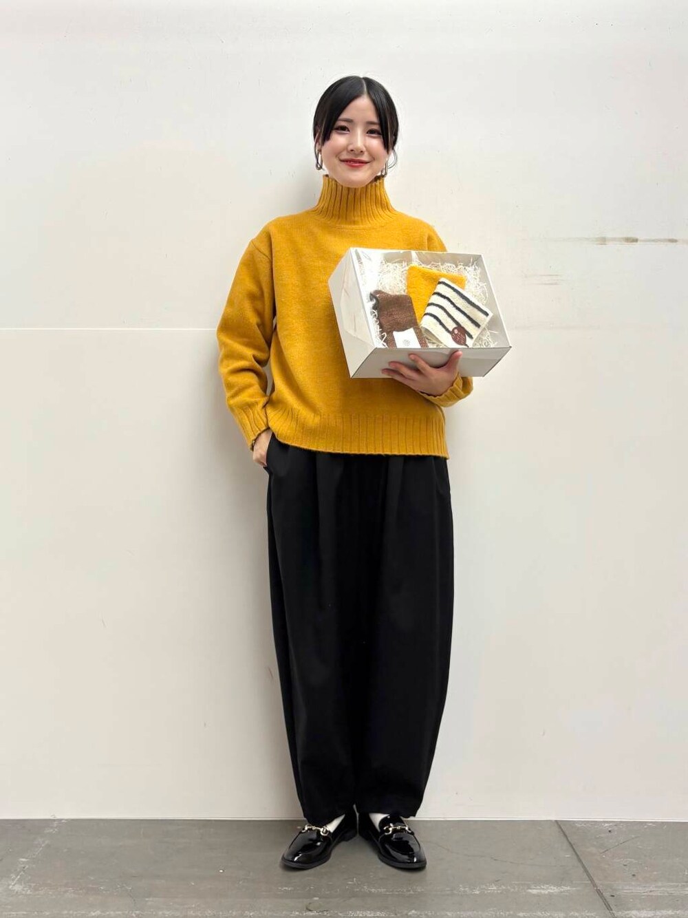 ブラック系のローファー、イエロー系のニット/セーター、ブラック系のその他パンツを着用したレディースの冬コーディネートの2枚目の写真