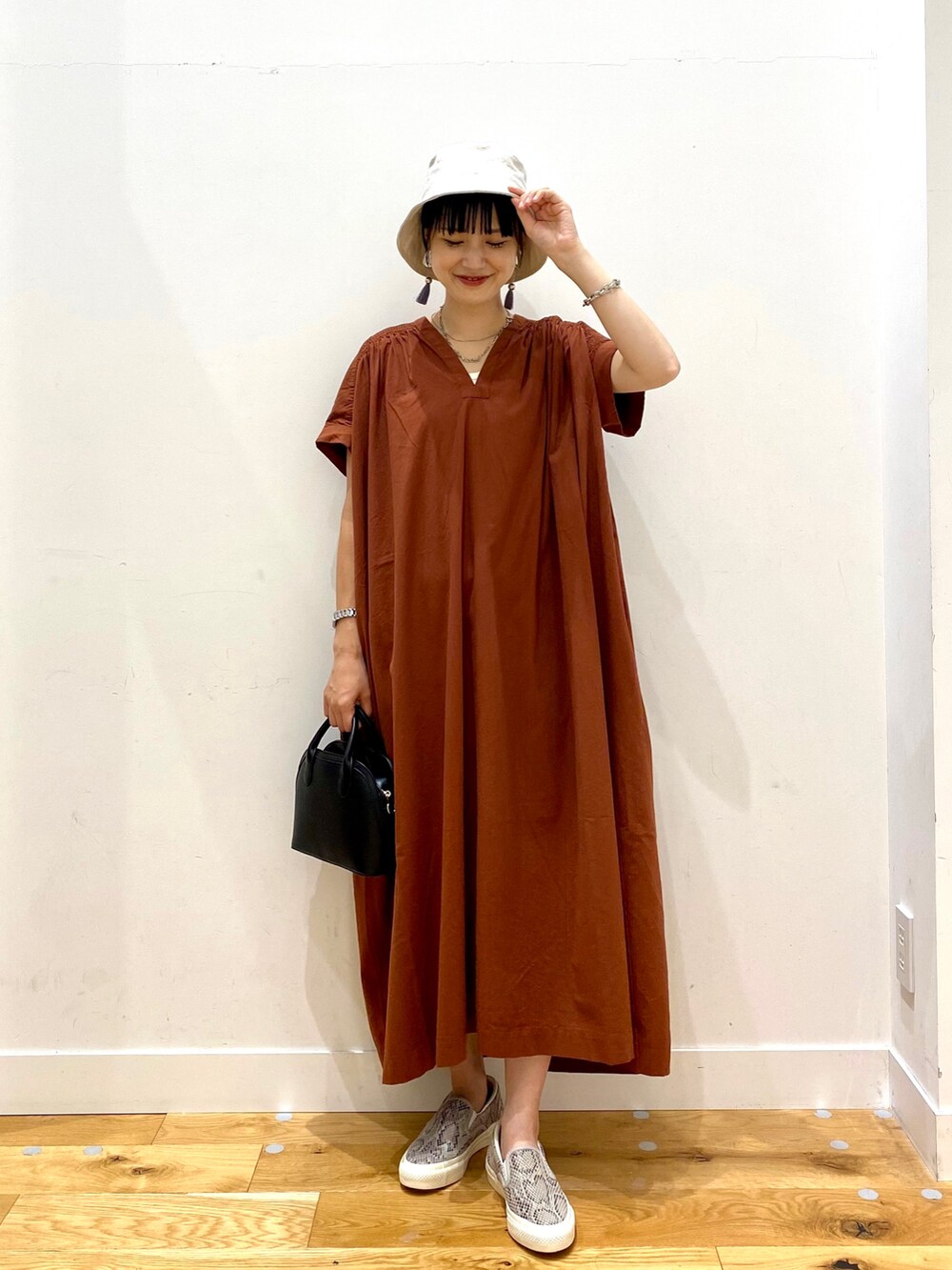 レッド系のワンピース、ブラック系のショルダーバッグ、ベージュ系のハットを着用したレディースの夏コーディネートの2枚目の写真