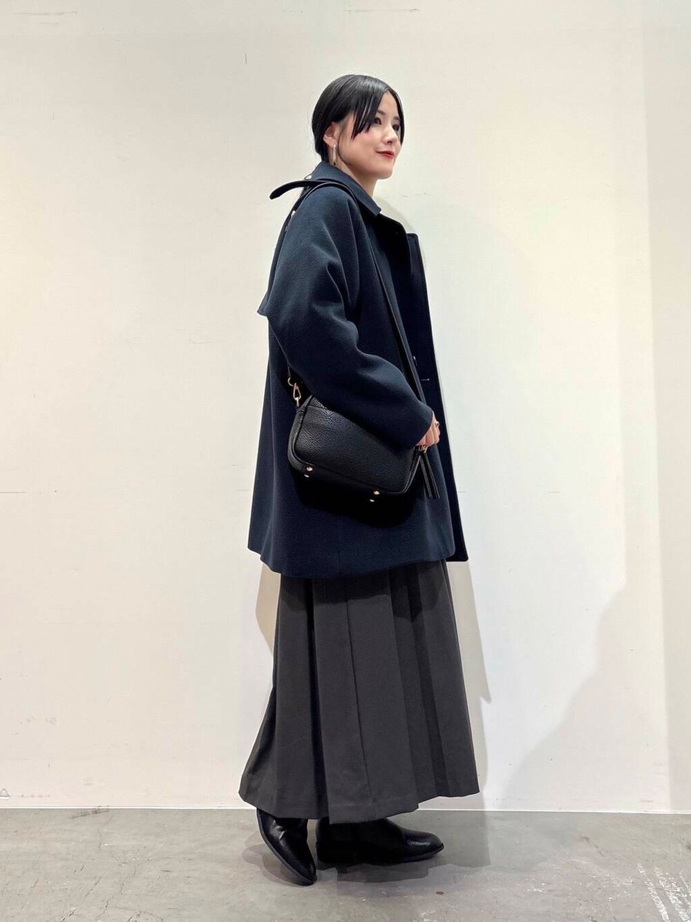 ブラック系のショルダーバッグ、グレー系のスカート、ブラック系のブーツを着用したレディースの冬コーディネートの2枚目の写真