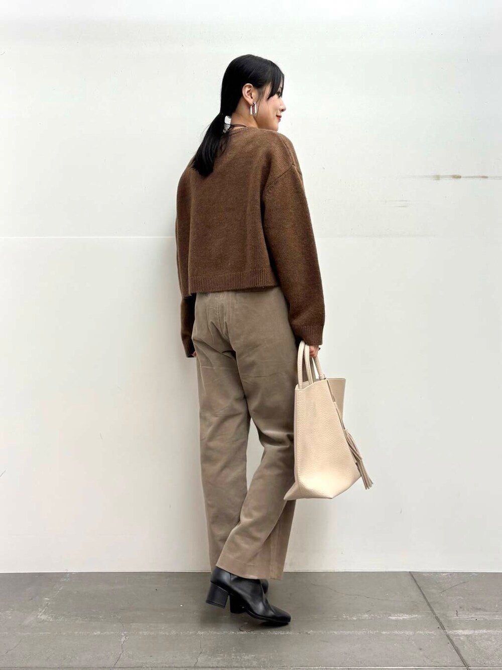 ブラック系のブーツ、ホワイト系のトートバッグ、ベージュ系のその他パンツを着用したレディースの冬コーディネートの3枚目の写真