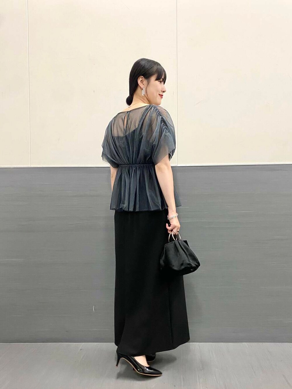 ブラック系のパンプス、ブラック系のハンドバッグ、ブラック系のワンピースを着用したレディースの秋コーディネートの4枚目の写真