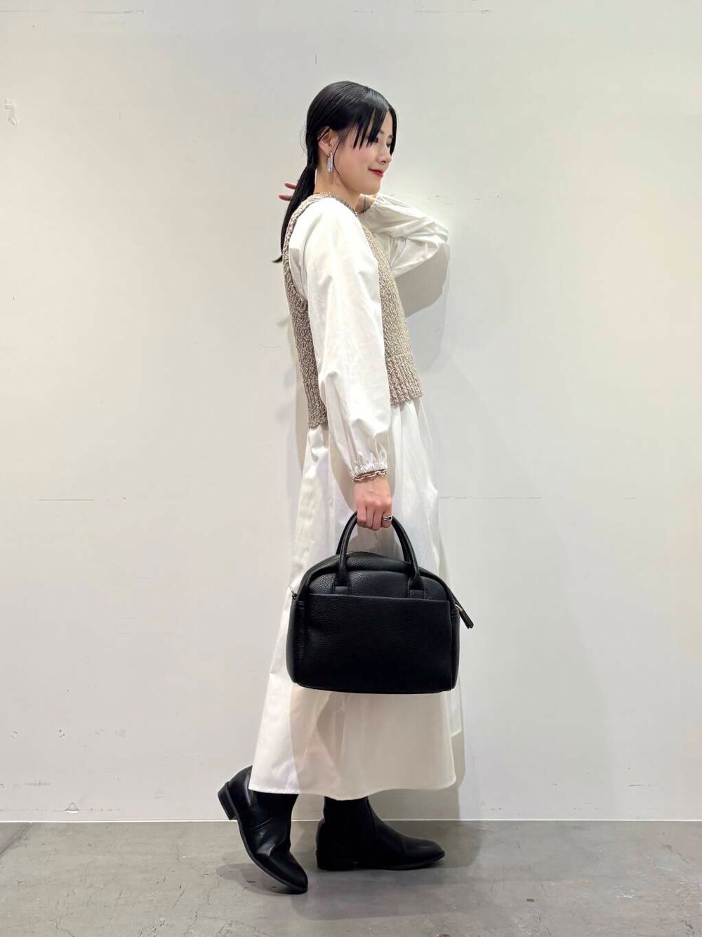 ブラック系のボストンバッグ、ブラウン系のダウンジャケット/コート、ブラック系のブーツを着用したレディースの冬コーディネートの2枚目の写真