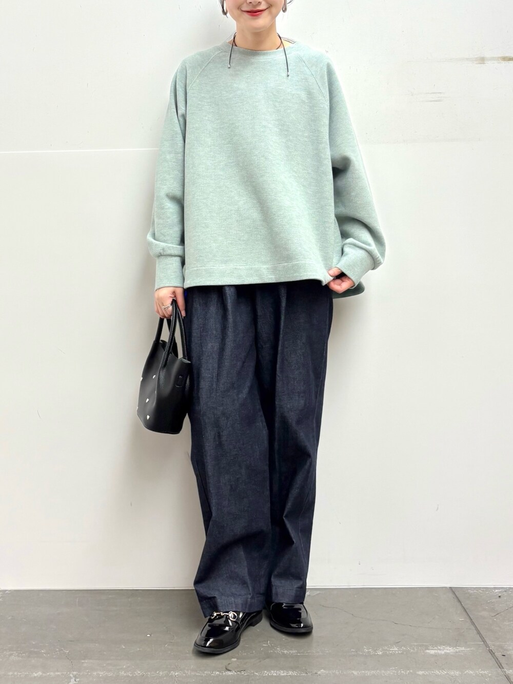 グリーン系のTシャツ/カットソー、ブルー系のデニムパンツ、ブラック系のショルダーバッグを着用したレディースの冬コーディネートの5枚目の写真