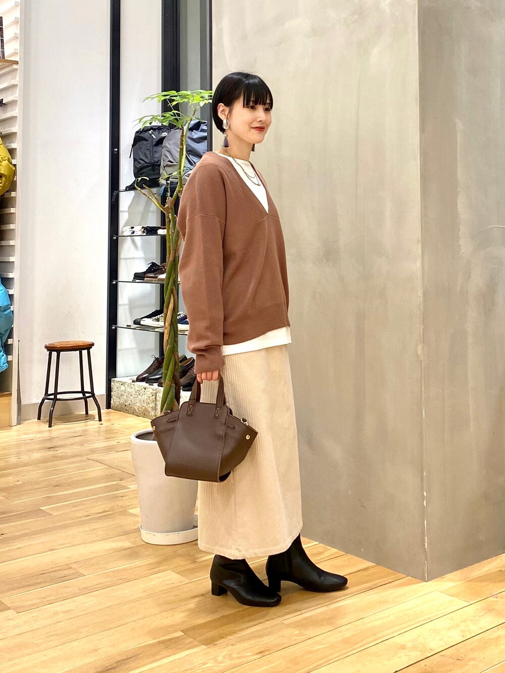 ブラウン系のニット/セーター、ホワイト系のTシャツ/カットソー、ホワイト系のスカートを着用したレディースの冬コーディネートの3枚目の写真