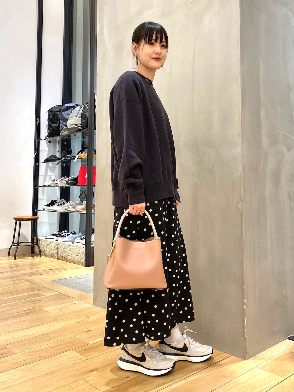 グレー系のスウェット、ブラック系のスカート、ピンク系のショルダーバッグを着用したレディースの春コーディネートの2枚目の写真