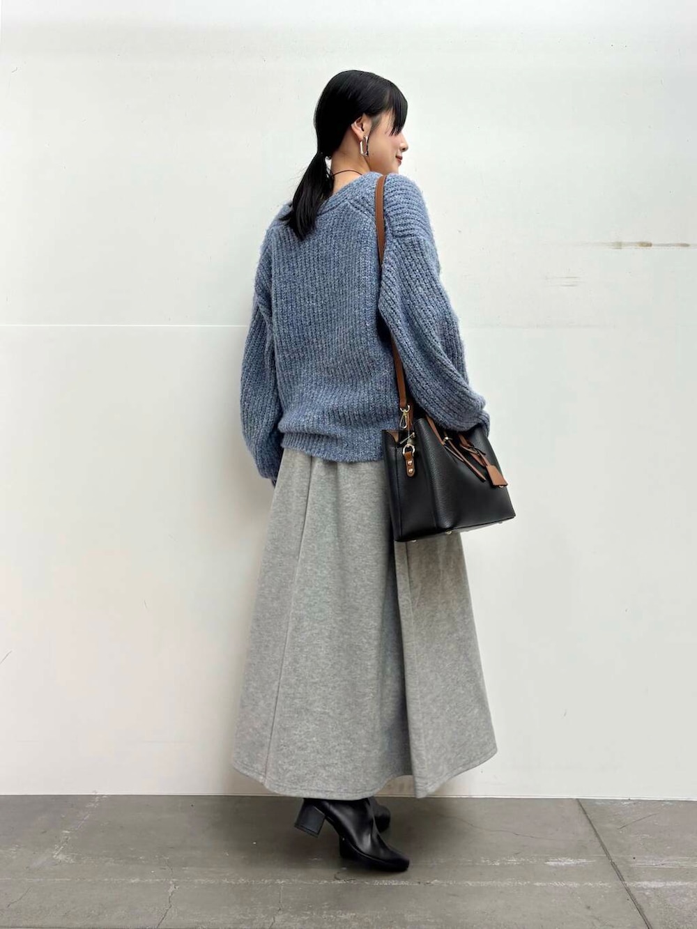 ブラック系のブーツ、ブラック系のトートバッグ、グレー系のスカートを着用したレディースの冬コーディネートの3枚目の写真