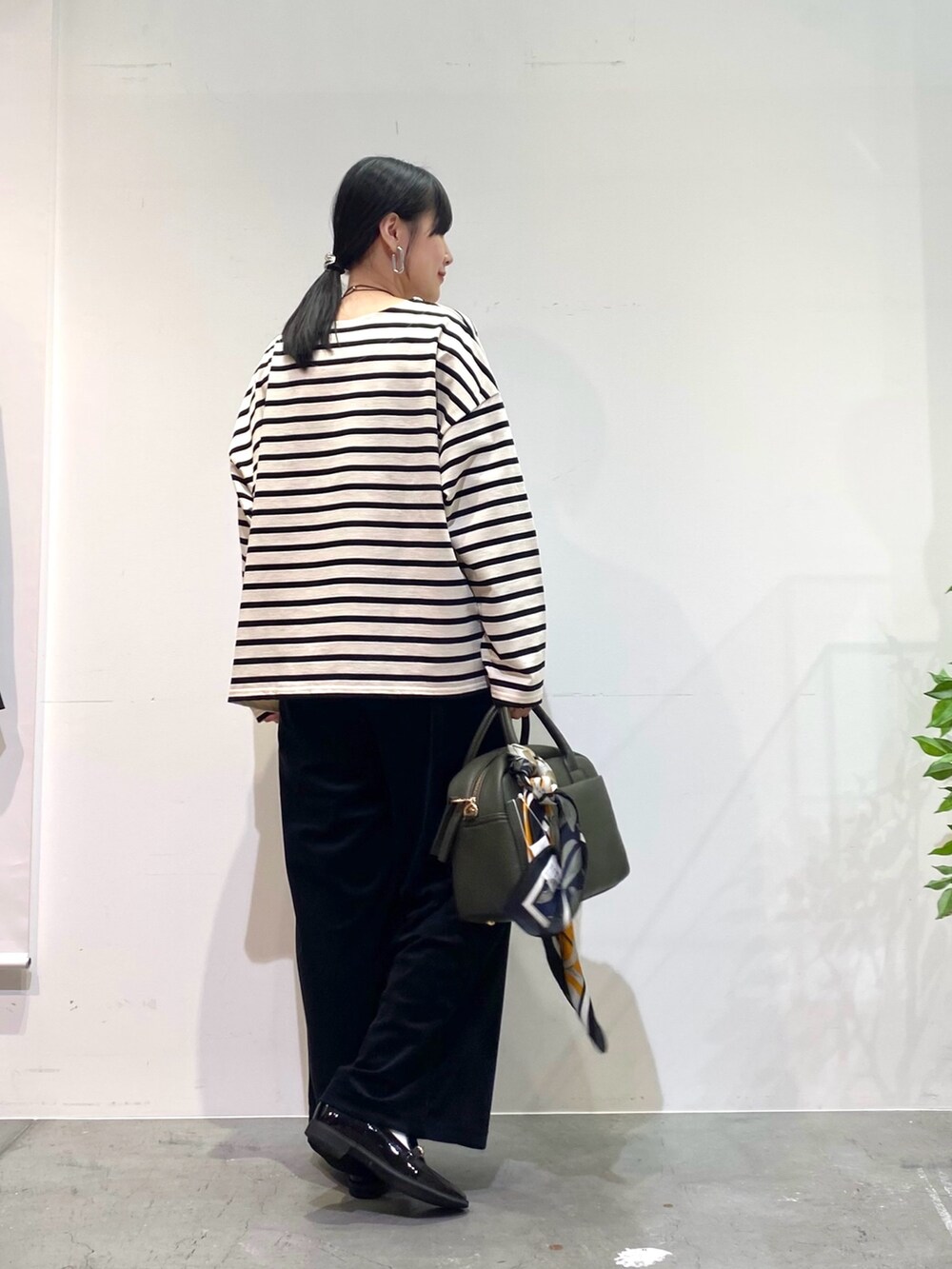 ホワイト系のTシャツ/カットソー、ブラック系のその他パンツ、グリーン系のボストンバッグを着用したレディースの秋コーディネートの5枚目の写真