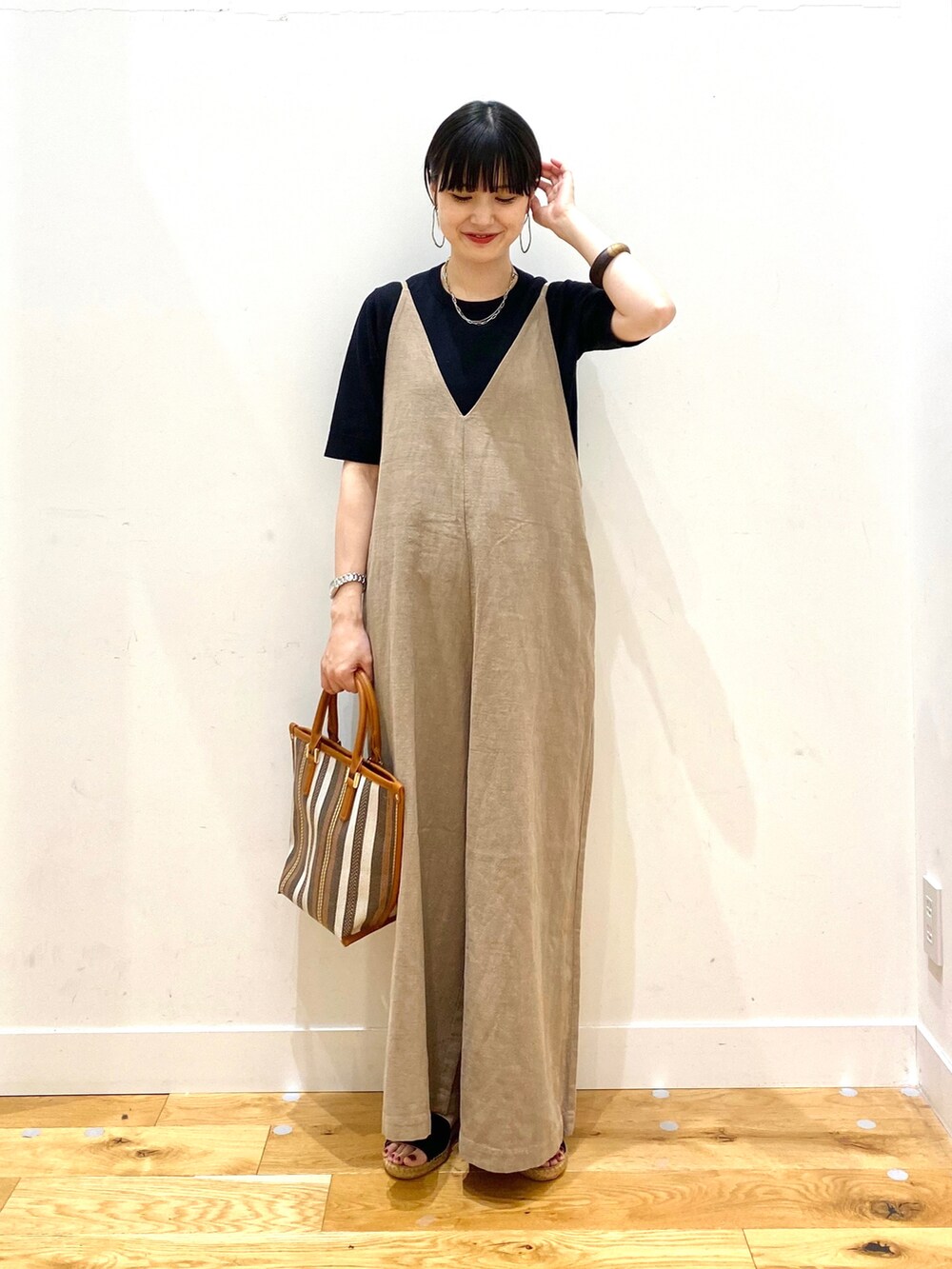 ブラック系のニット/セーター、ベージュ系のサロペット/オーバーオール、イエロー系のトートバッグを着用したレディースの春コーディネートの2枚目の写真