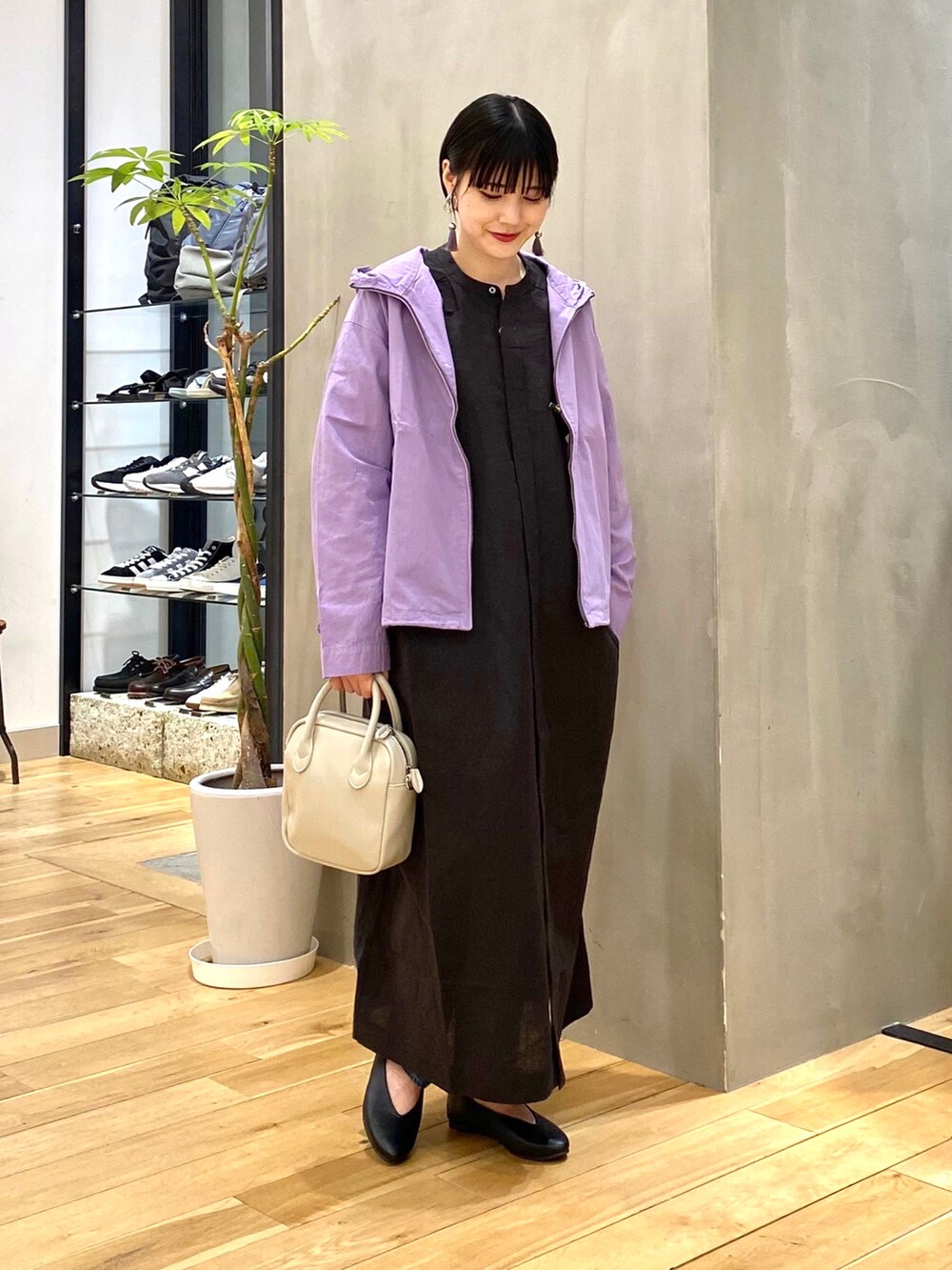 パープル系のブルゾン、ブルー系のデニムパンツ、ベージュ系のショルダーバッグを着用したレディースの春コーディネートの3枚目の写真