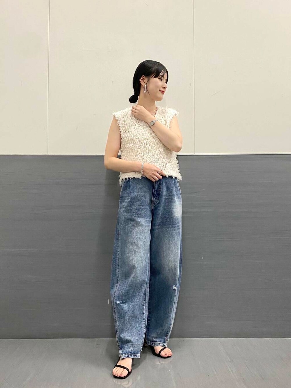 ブルー系のデニムパンツ、ホワイト系のベスト、ブラック系のサンダルを着用したレディースの夏コーディネートの2枚目の写真