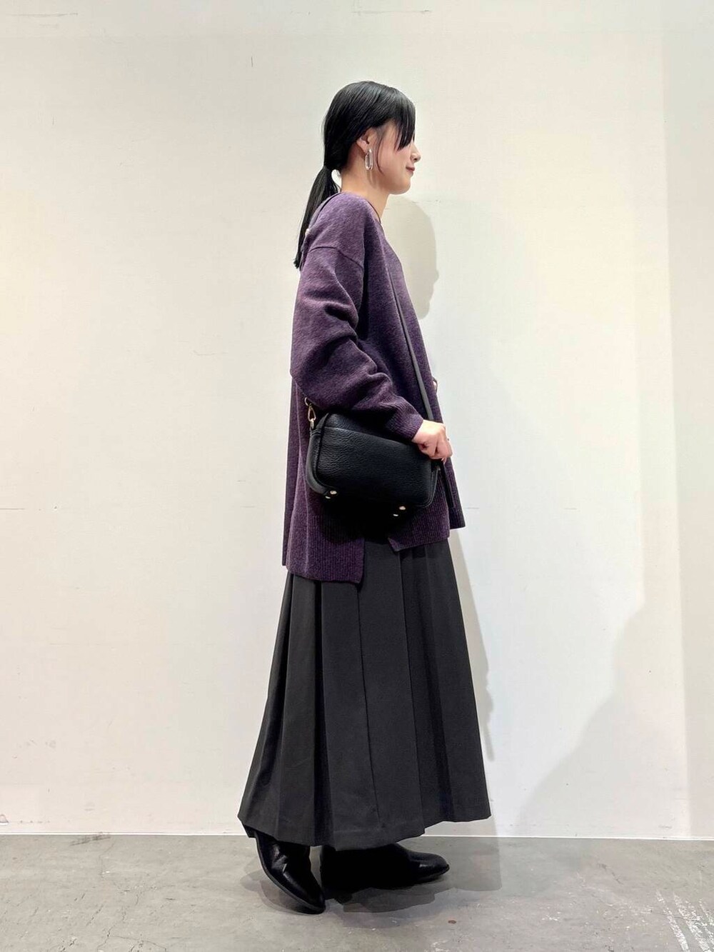 ブラック系のショルダーバッグ、グレー系のスカート、ブラック系のブーツを着用したレディースの冬コーディネートの5枚目の写真