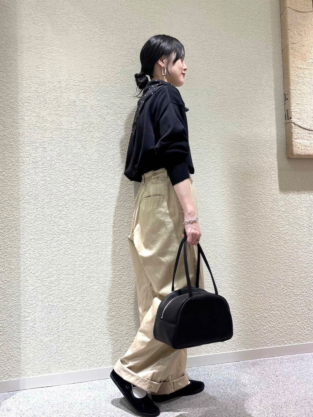 ブラック系のニット/セーター、ベージュ系のその他パンツ、ブラック系のバンダナ/スカーフを着用したレディースの春コーディネートの2枚目の写真