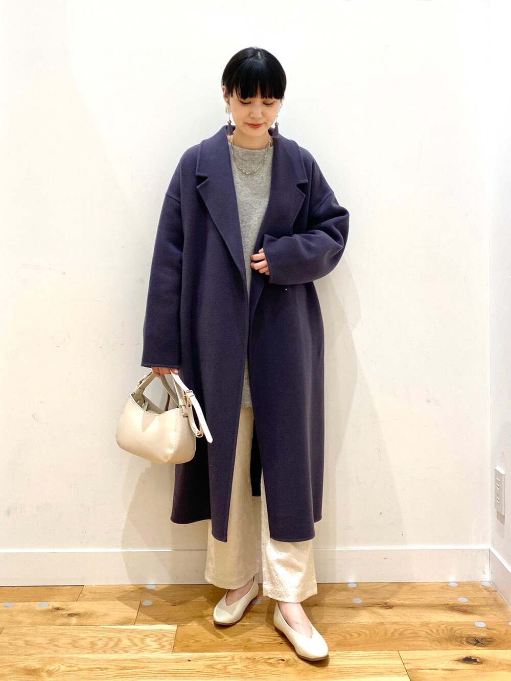 ブルー系のチェスターコート、グレー系のニット/セーター、ホワイト系のその他パンツを着用したレディースの冬コーディネートの2枚目の写真