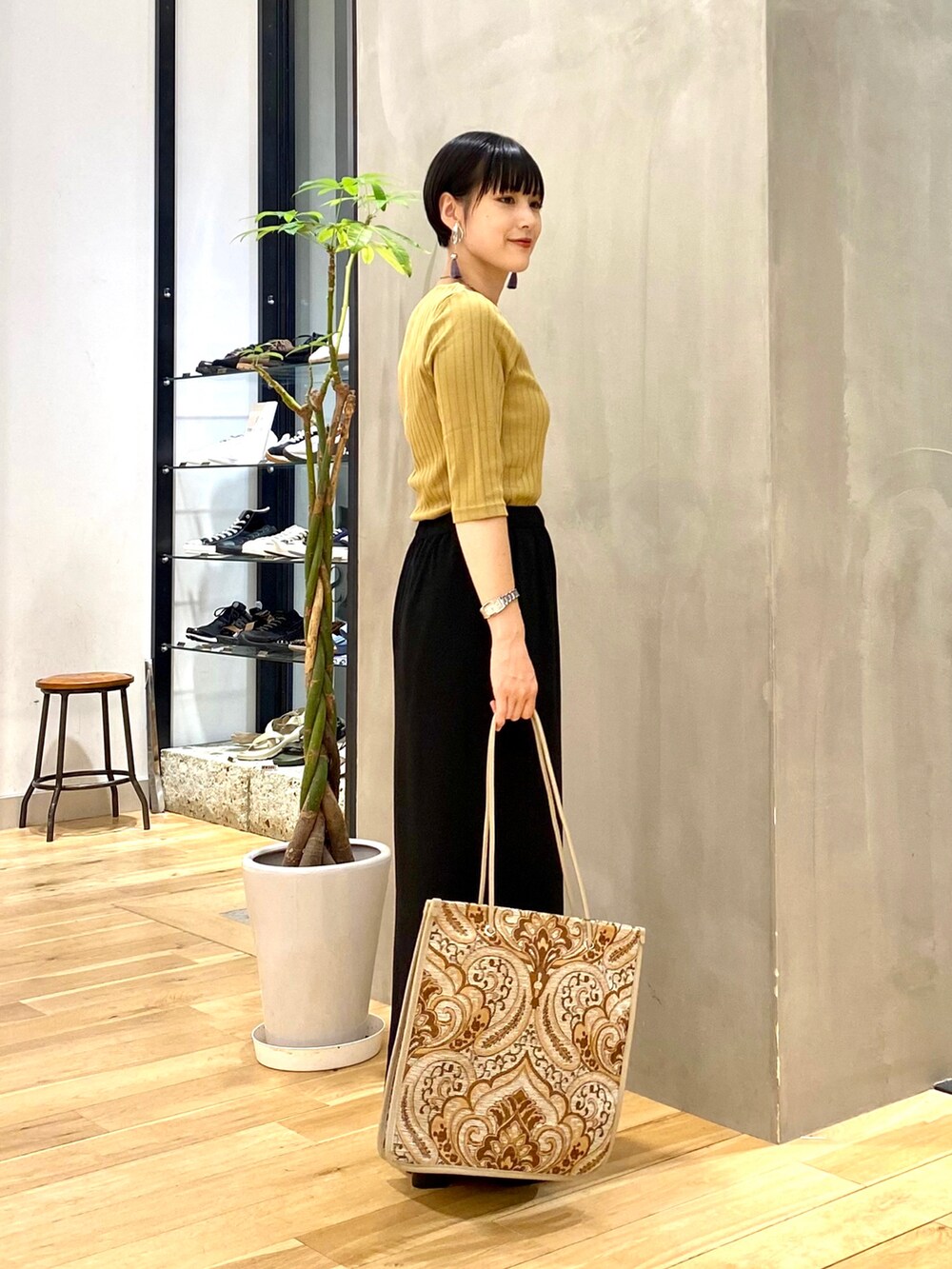 イエロー系のTシャツ/カットソー、ブラック系のスカート、ホワイト系のトートバッグを着用したレディースの秋コーディネートの3枚目の写真