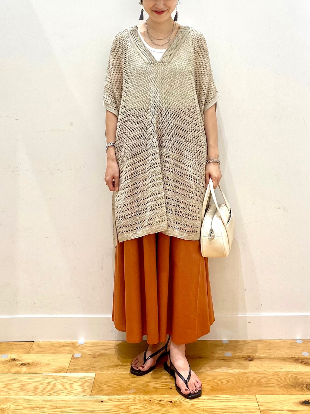 ベージュ系のニット/セーター、ホワイト系のタンクトップ、オレンジ系のスカートを着用したレディースの夏コーディネートの4枚目の写真