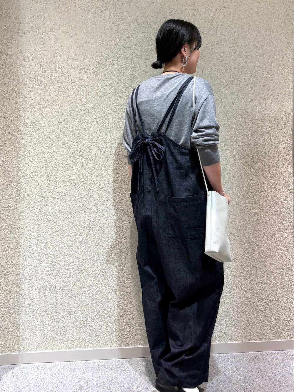 グレー系のニット/セーター、ブルー系のサロペット/オーバーオール、ホワイト系のショルダーバッグを着用したレディースの秋コーディネートの3枚目の写真