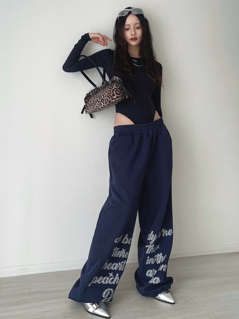 シルバー系のサンダル、ブルー系のスウェットパンツ、ブラウン系のショルダーバッグを着用したレディースの秋コーディネートの3枚目の写真