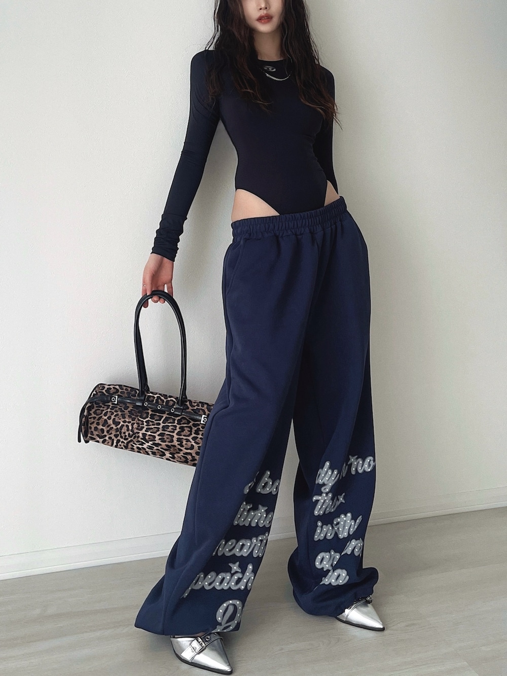 シルバー系のサンダル、ブルー系のスウェットパンツ、ブラウン系のショルダーバッグを着用したレディースの秋コーディネートの2枚目の写真