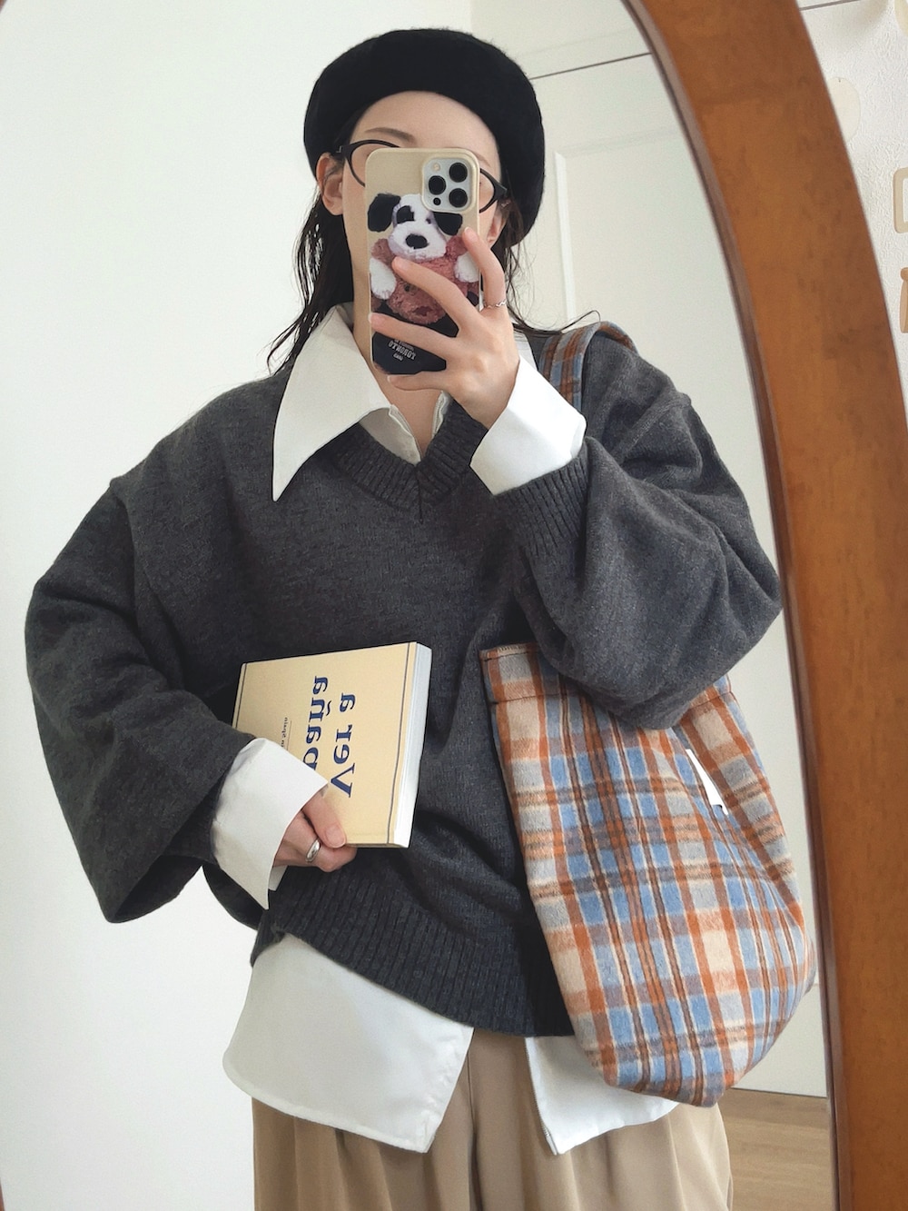 グレー系のニット/セーター、ホワイト系のシャツ/ブラウス、ベージュ系のパンツを着用したレディースの秋コーディネートの2枚目の写真