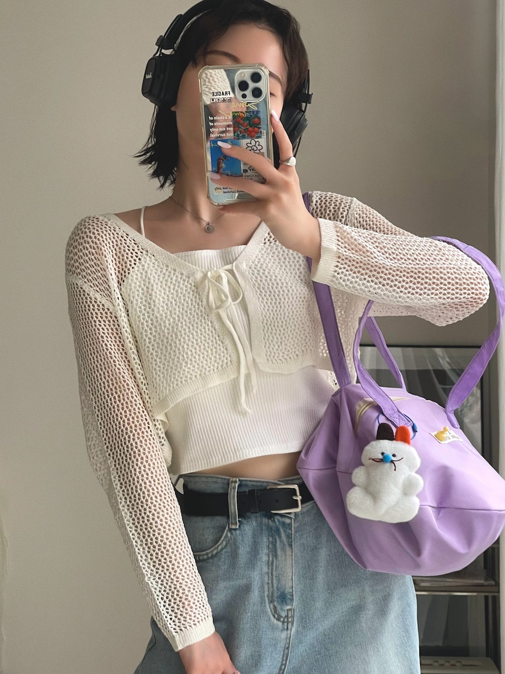 パープル系のショルダーバッグ、ブルー系のデニムパンツ、ホワイト系のカーディガン/ボレロを着用したレディースの春コーディネートの4枚目の写真