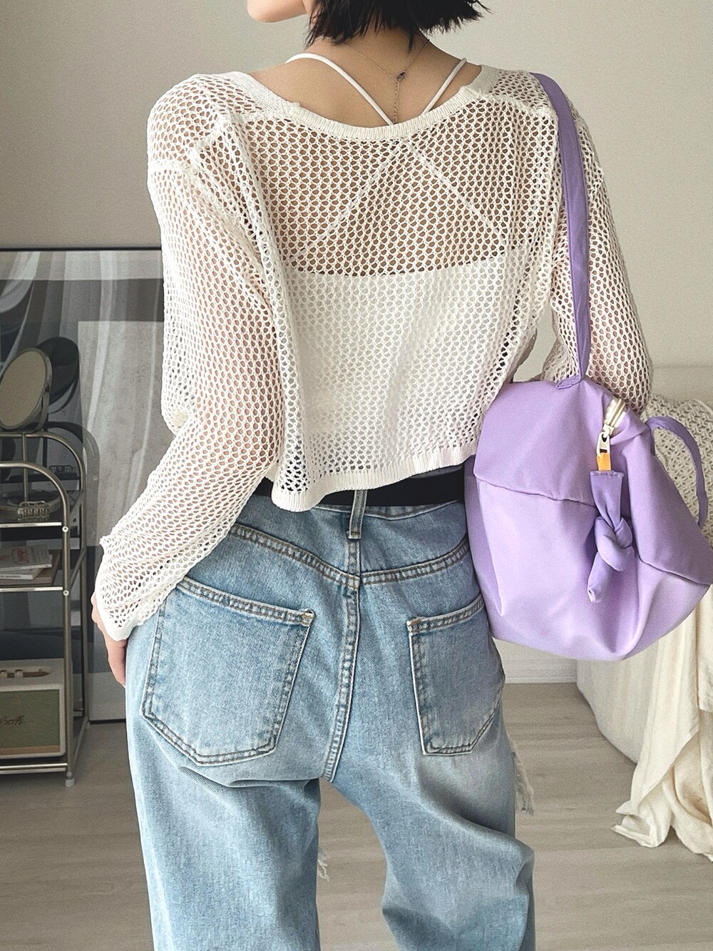 パープル系のショルダーバッグ、ブルー系のデニムパンツ、ホワイト系のカーディガン/ボレロを着用したレディースの春コーディネートの3枚目の写真