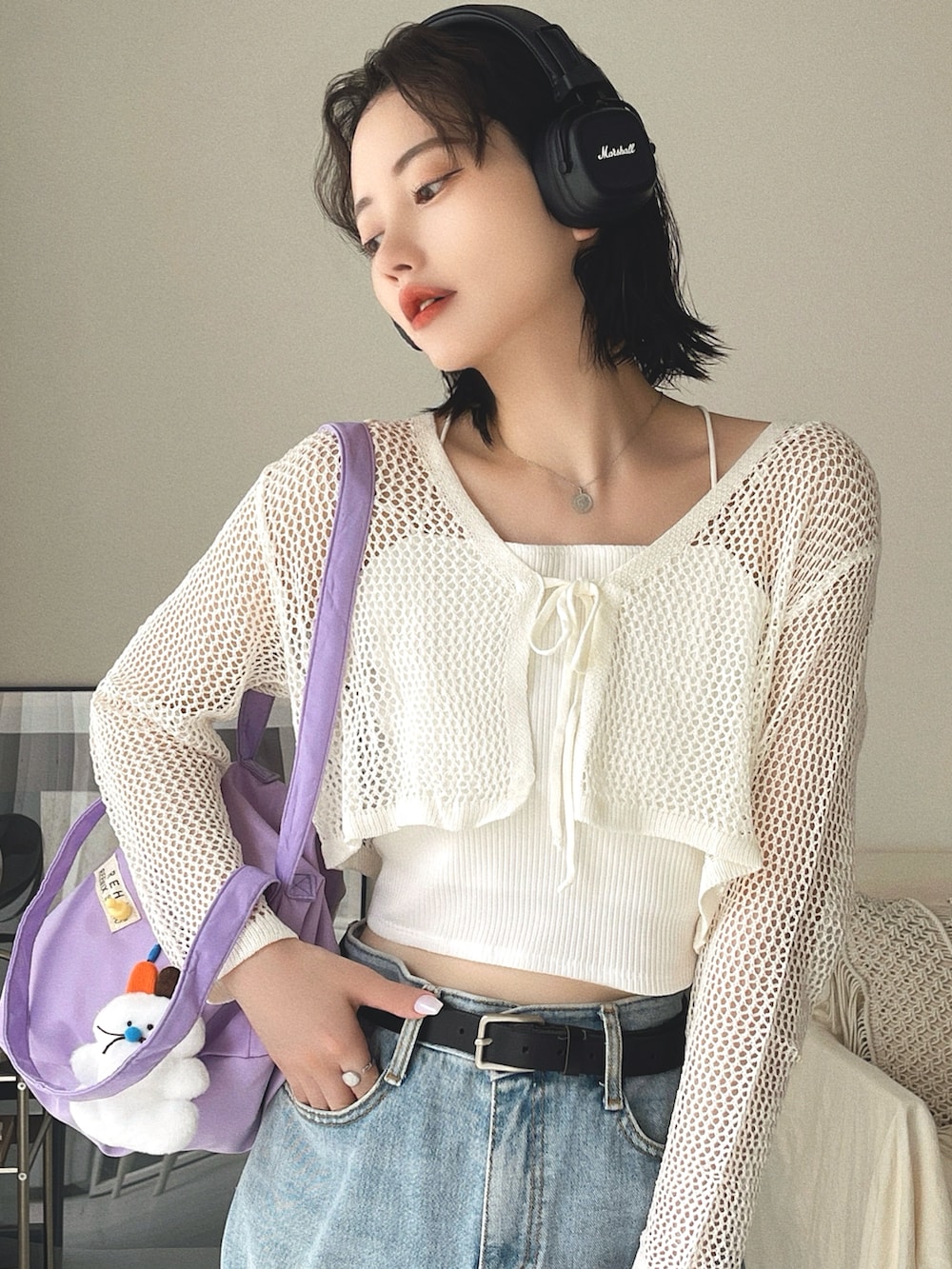 パープル系のショルダーバッグ、ブルー系のデニムパンツ、ホワイト系のカーディガン/ボレロを着用したレディースの春コーディネートの2枚目の写真