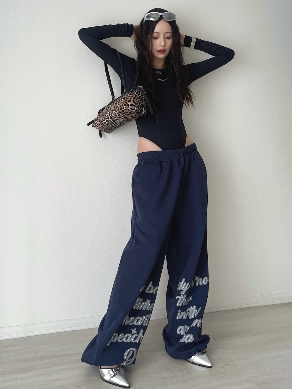 シルバー系のサンダル、ブルー系のスウェットパンツ、ブラウン系のショルダーバッグを着用したレディースの秋コーディネートの4枚目の写真