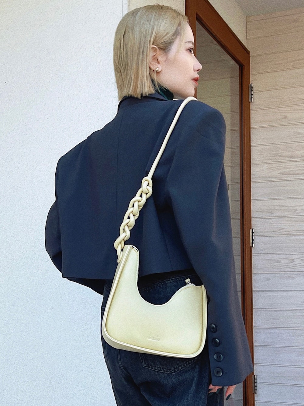 イエロー系のショルダーバッグ、グリーン系のニット/セーター、ブラック系のデニムパンツを着用したレディースの冬コーディネートの2枚目の写真