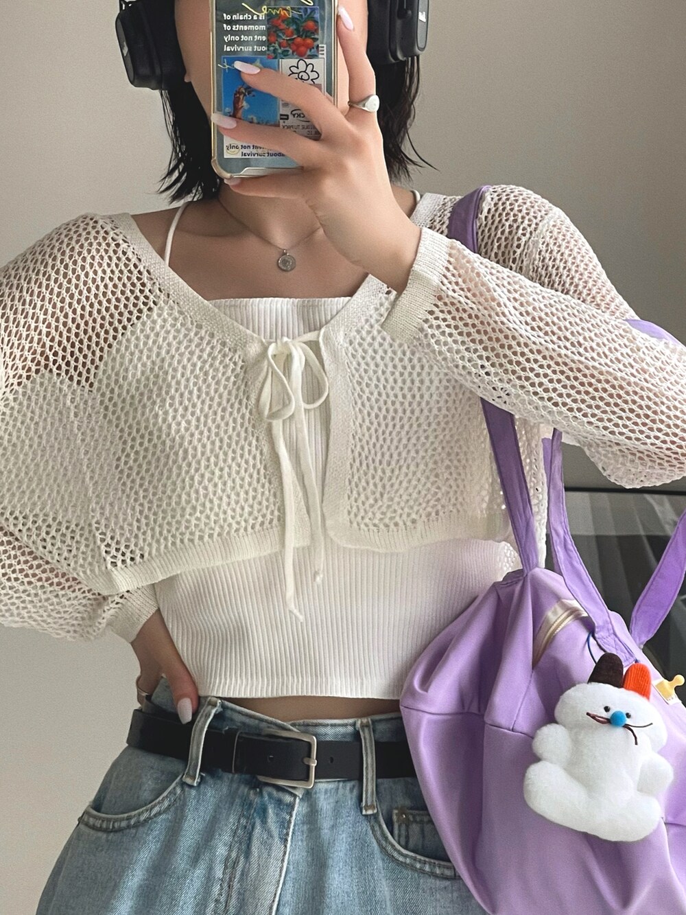 パープル系のショルダーバッグ、ブルー系のデニムパンツ、ホワイト系のカーディガン/ボレロを着用したレディースの春コーディネートの5枚目の写真