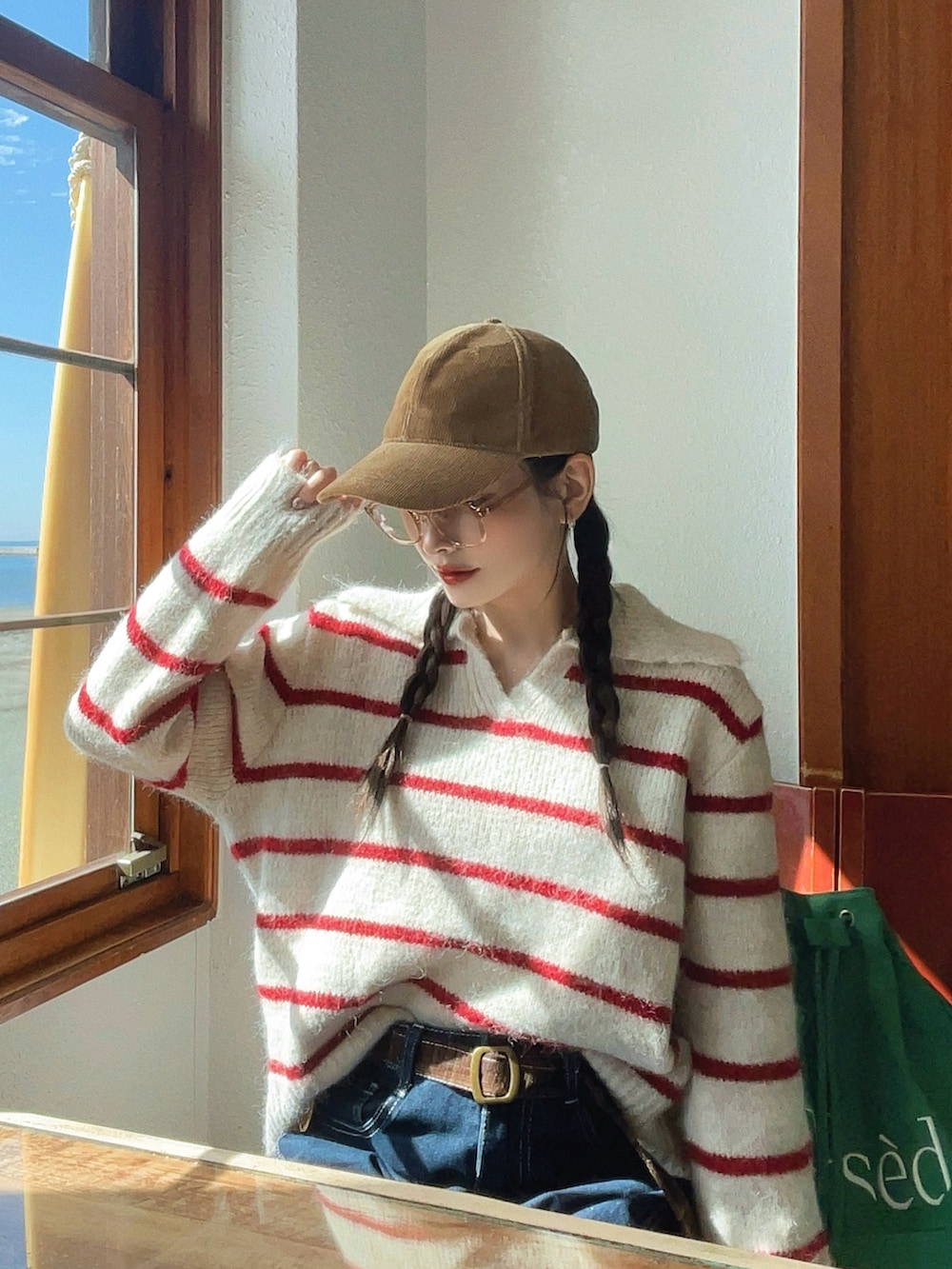 ブルー系のデニムパンツ、グリーン系のバックパック/リュック、ベージュ系のブーツを着用したレディースの秋コーディネートの3枚目の写真